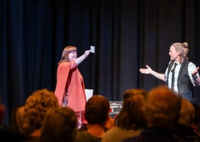 German magician Henry Oz as a volunteer holds up a revealed card during a theater show on Lopez Island