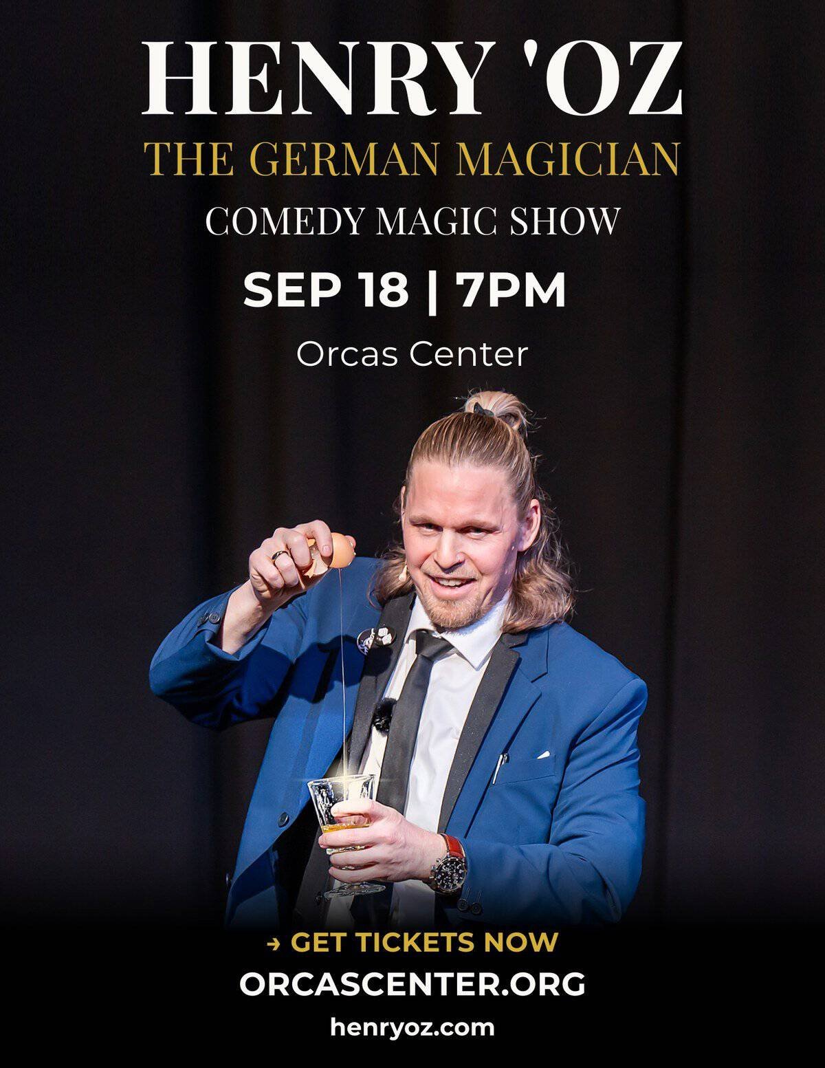 German magician Henry Oz on stage in a blue suit holding a red silk during a theater show in the San Juan Islands