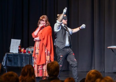 Henry Oz blindfolded giving thumbs up as a shocked volunteer reacts during a magic show in the San Juan Islands