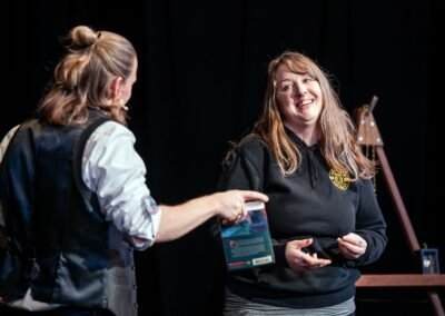 Magician Henry Oz handing a book to a volunteer for a mentalism routine during a theater show on Lopez Island