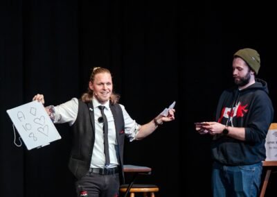 Henry Oz revealing a mentalism prediction on a whiteboard during a magic show in the San Juan Islands